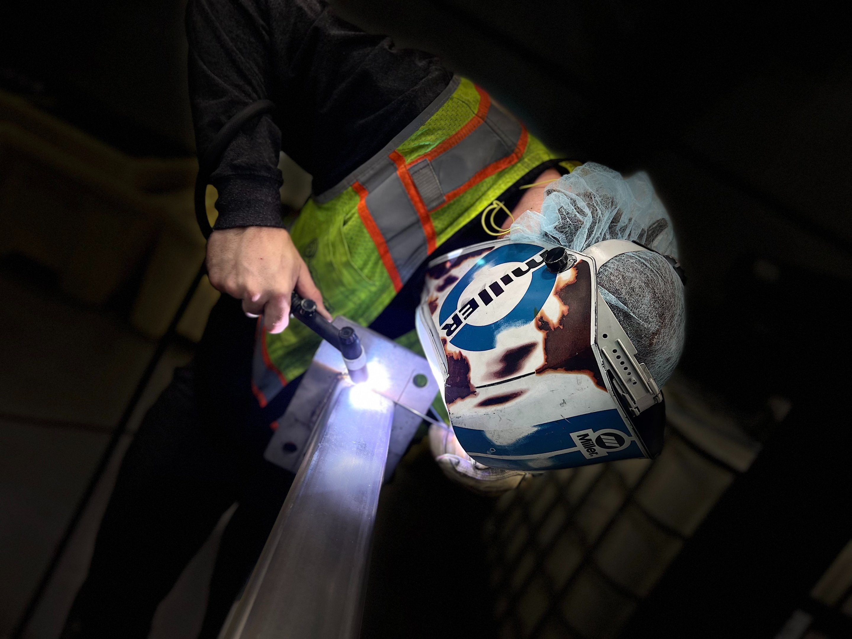 Welder working on a stainless pipe assembly in a production facility